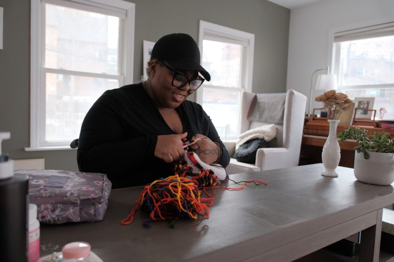 A person knitting on a table  Description automatically generated